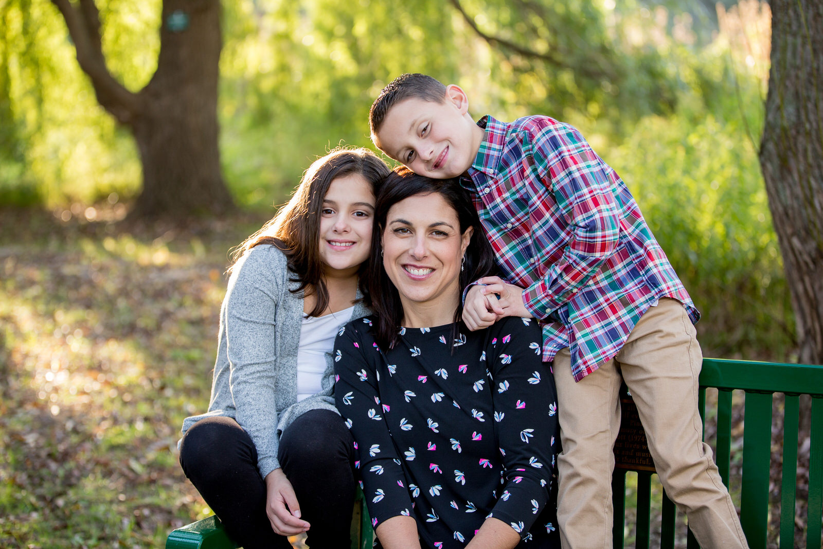 Mother and her two children sitting on a bench for family portraits in Erie, PA