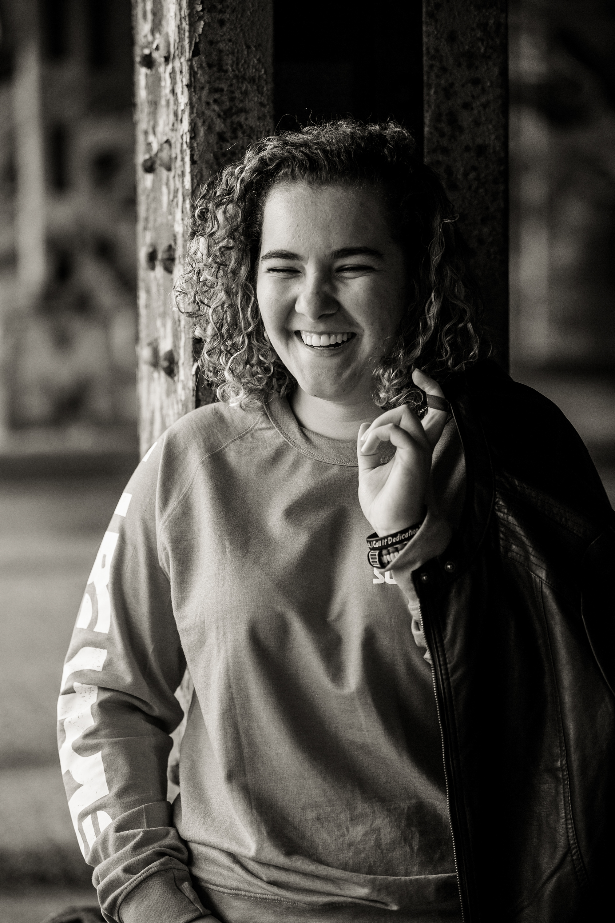 Erie senior portraits of laughing girl holding leather jacket under 14th St. underpass