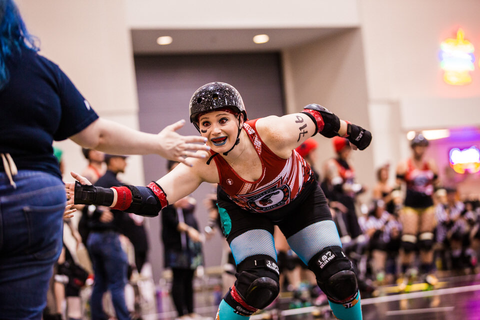 Eerie Roller Girls' player giving high fives to fans at home bout