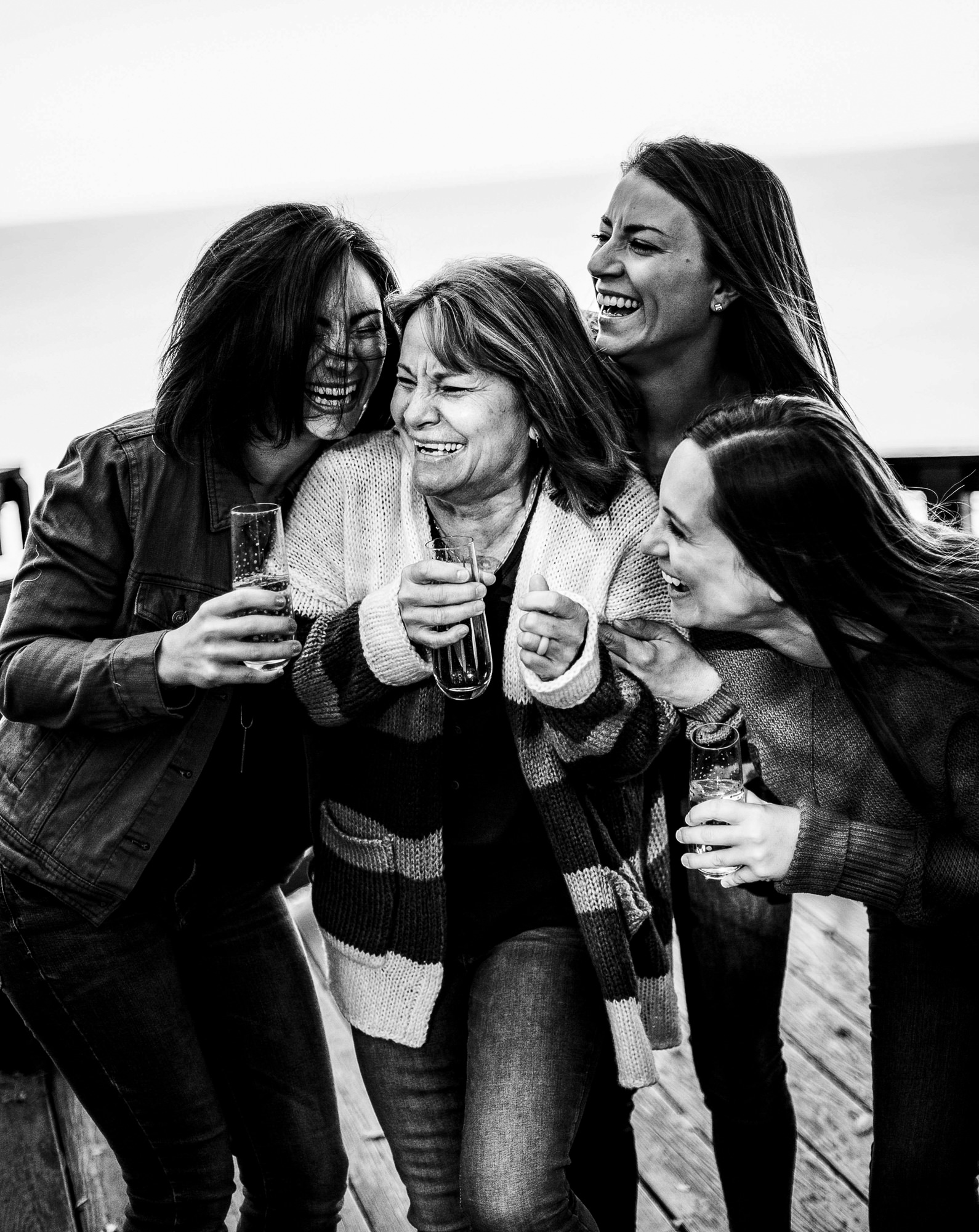 Mother and three daughters laugh over glasses of champagne for family portraits in Erie, PA