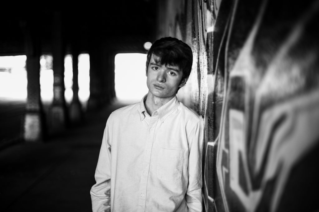 Young man standing in 14th Street underpass during senior photos in Downtown Erie