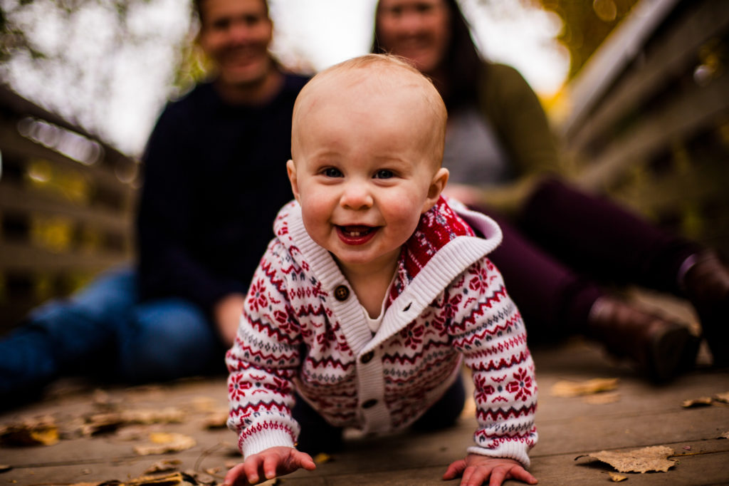 Baby crawling while parents smile during family photos at Frontier Park