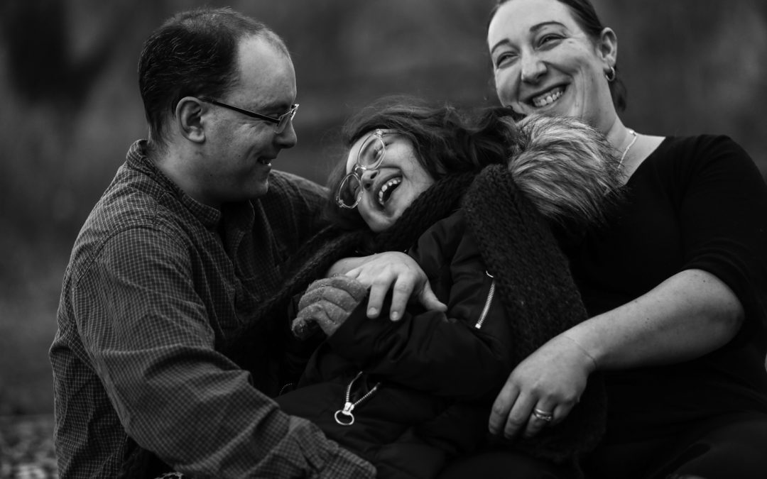 Father, daughter and mother laugh together during family portraits session in Frontier Park