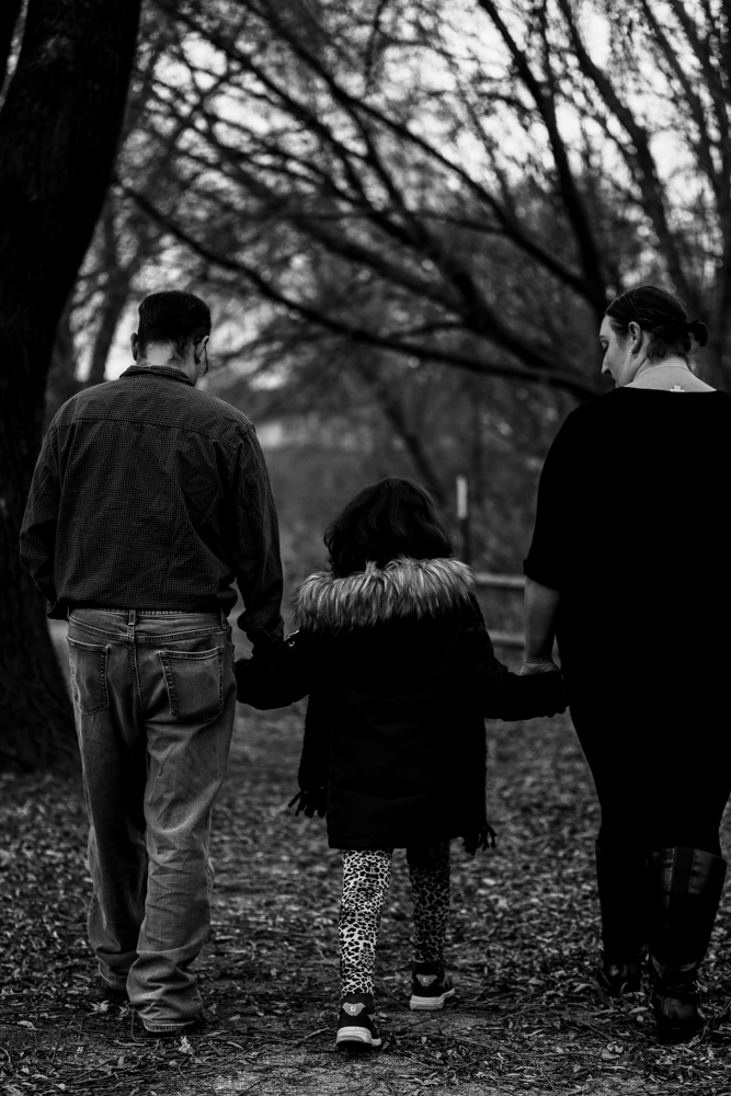 MOther, father and child walking through Frontier Park while all holding hands