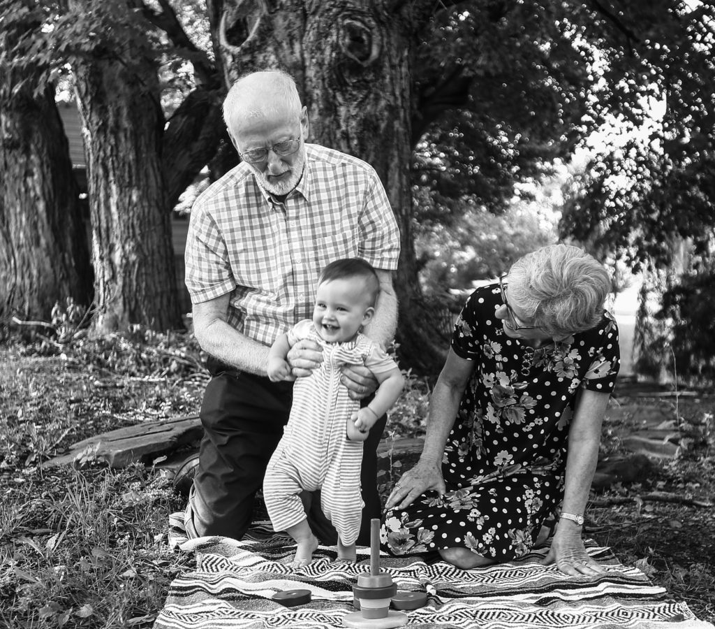 Grandparents play with infant grandson during 50th wedding anniversary family photo session