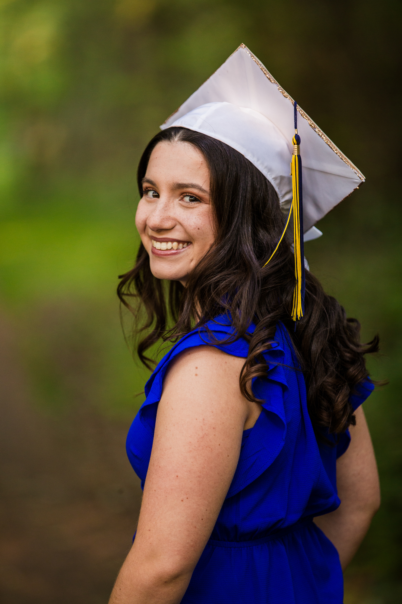 Girl wearing graduation cap smiles at the camera while looking over her shoulder for Erie PA senior portraits