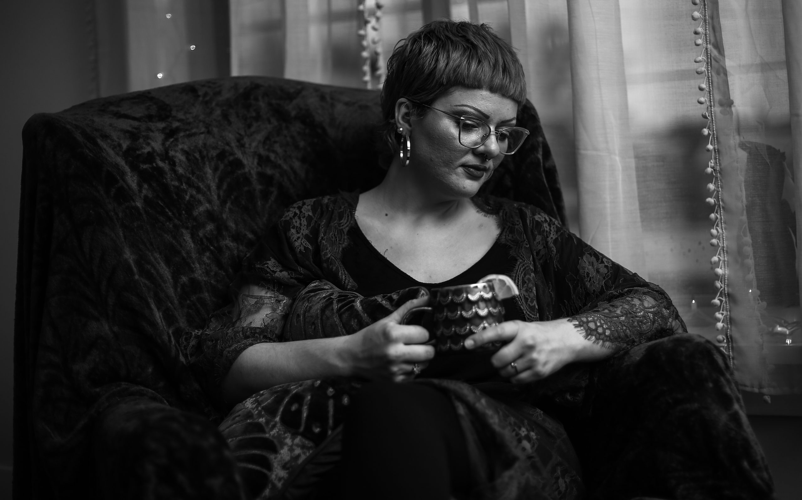 Woman holding mug, sitting on soft furniture.
