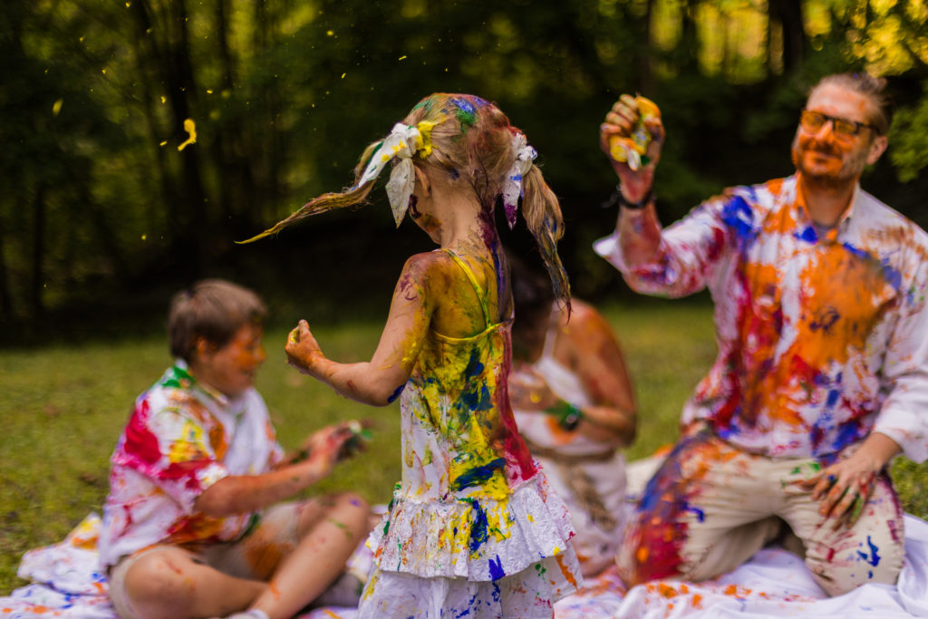 A family in a park throwing paint at each other and laughing. Taken by a professional photographer.